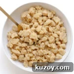 Unbaked butter streusel topping in a white bowl with gold serving spoon.