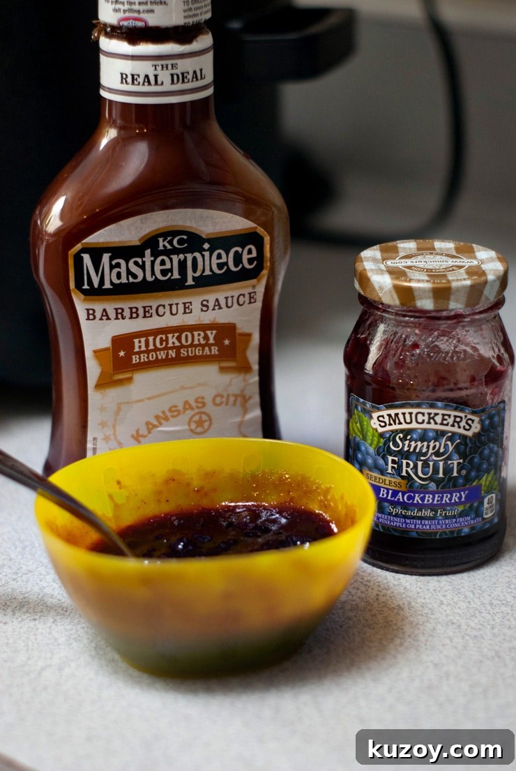 KC Masterpiece BBQ Sauce and Smuckers Blackberry Jam on a white table.