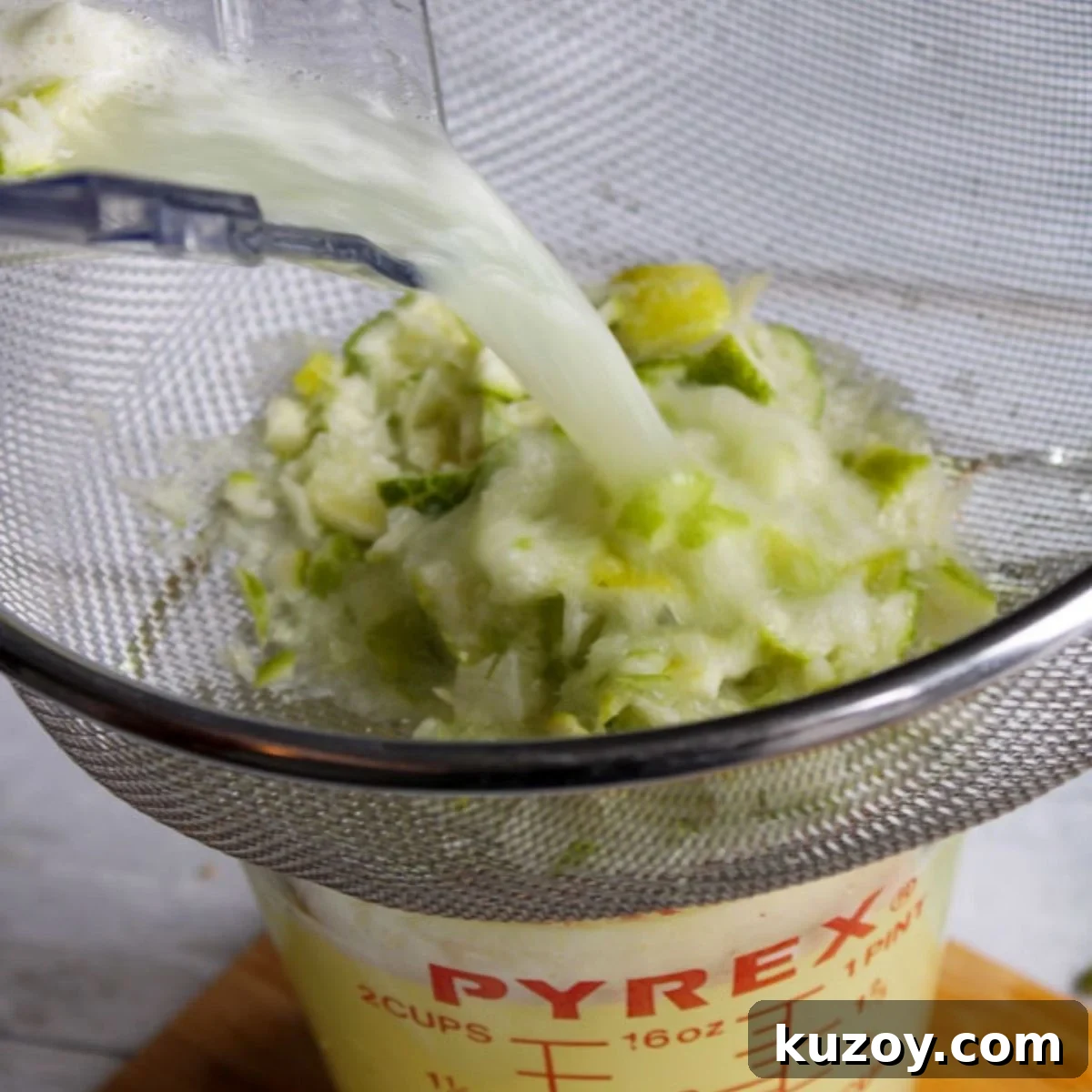 Straining lime juice in a wire strainer.