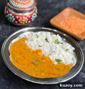 Delicious red lentil curry served with fluffy white rice on a traditional metal plate. Perfect for a.