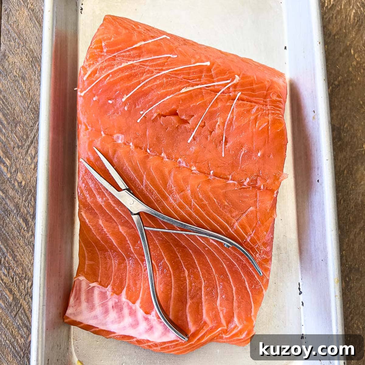 Removing pin bones from raw salmon with pliers.