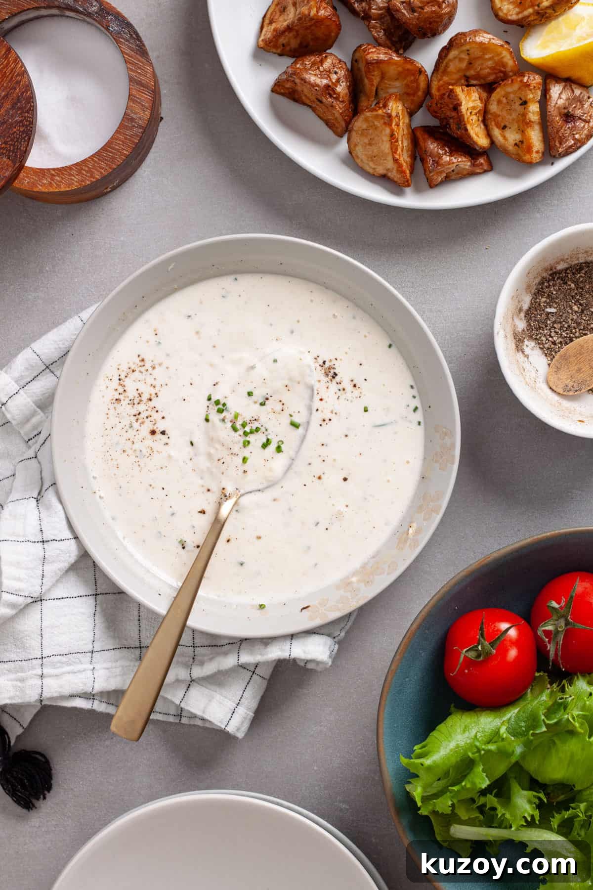 A bowl of horseradish aioli with a salad to the side and crispy roasted potatoes to the other side.