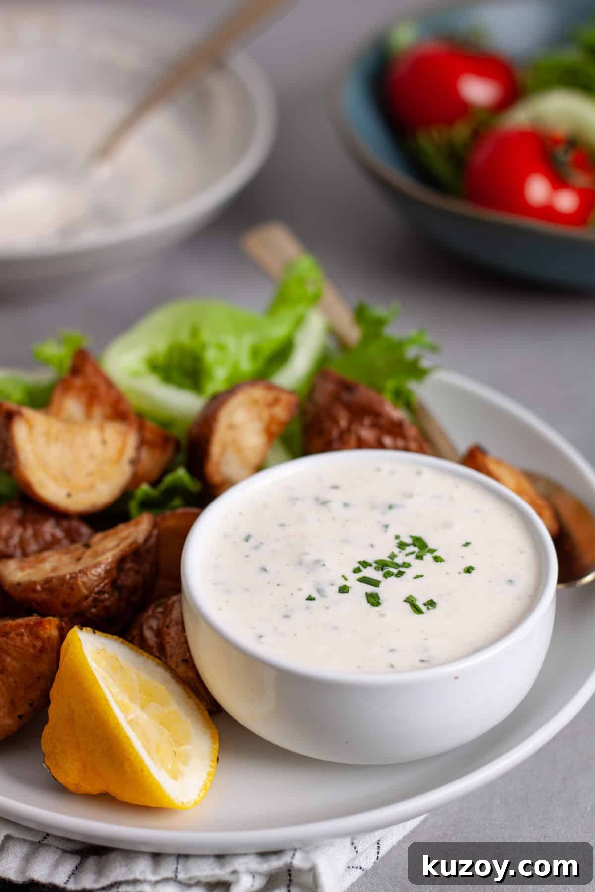 A closeup of horseradish aioli in a small bowl on a platter of crispy roasted potatoes.