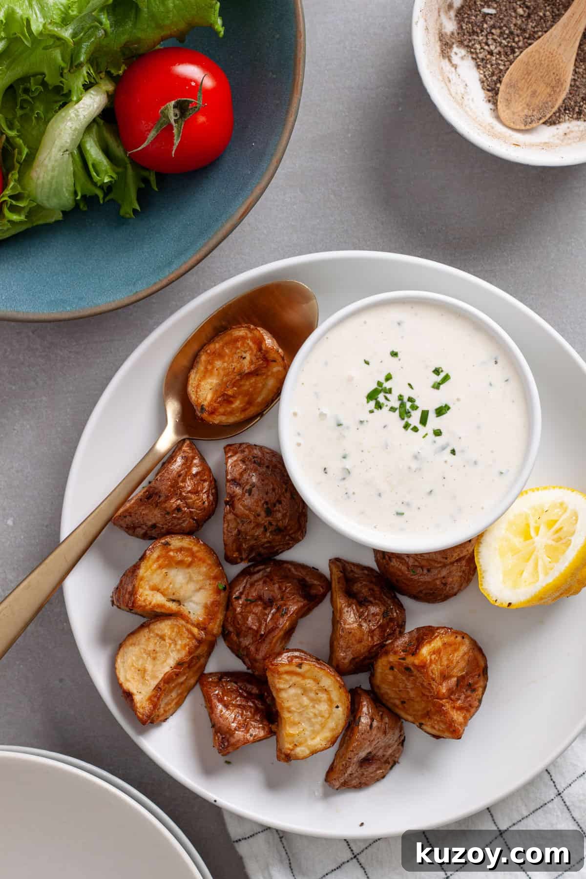 A plate of roasted potatoes with a small bowl of horseradish aioli to the side.