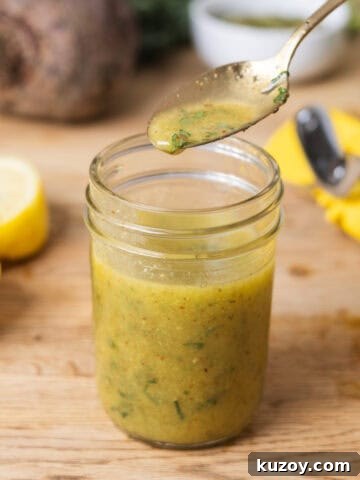 A glass jar of lemon Dijon dressing on Butcherblock countertop.