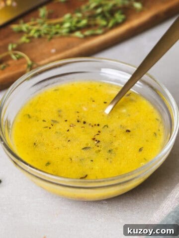 A close-up of lemon thyme vinaigrette in a glass bowl with a spoon inside.