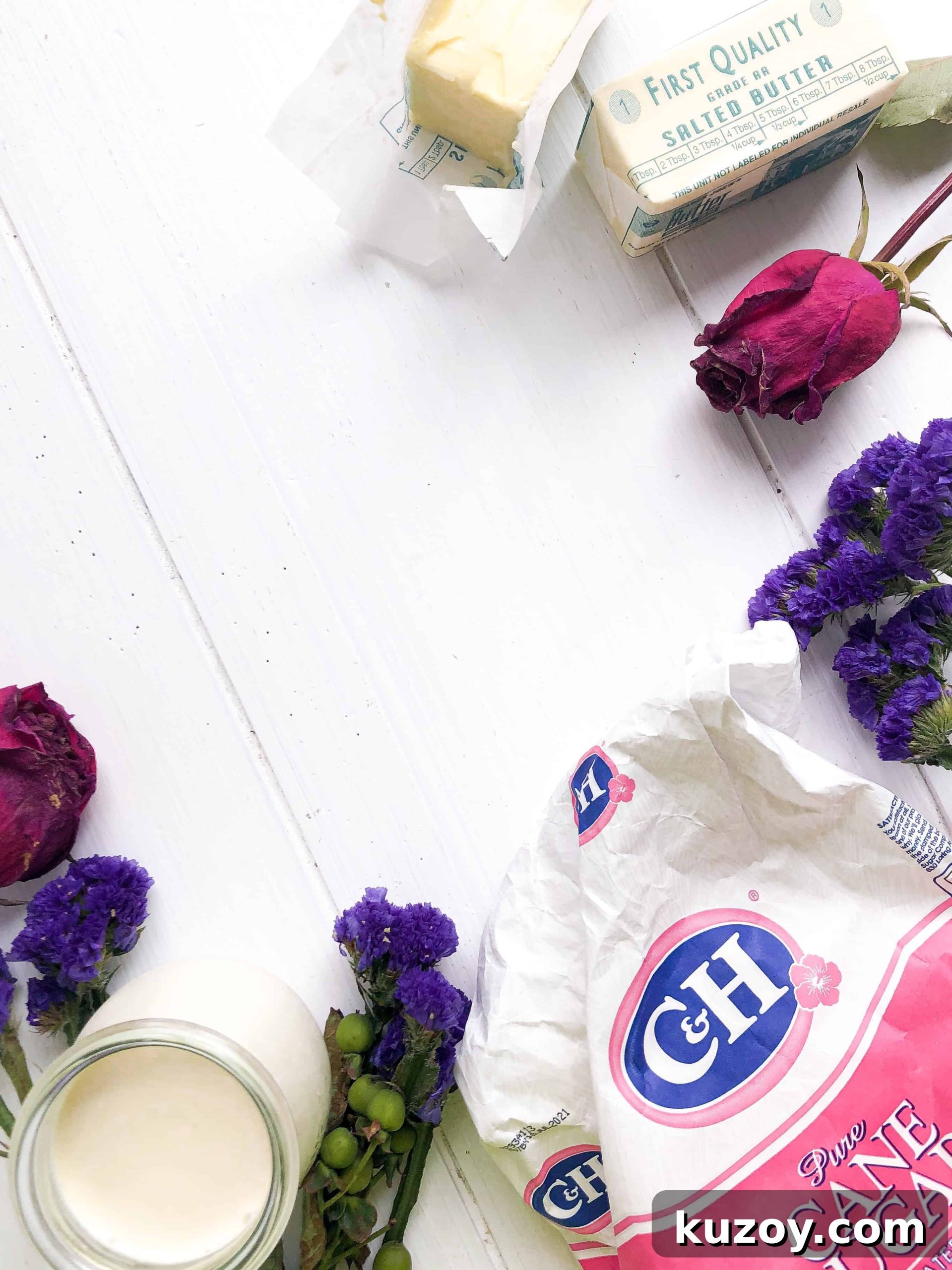 Sugar, butter, cream and flowers on a white table