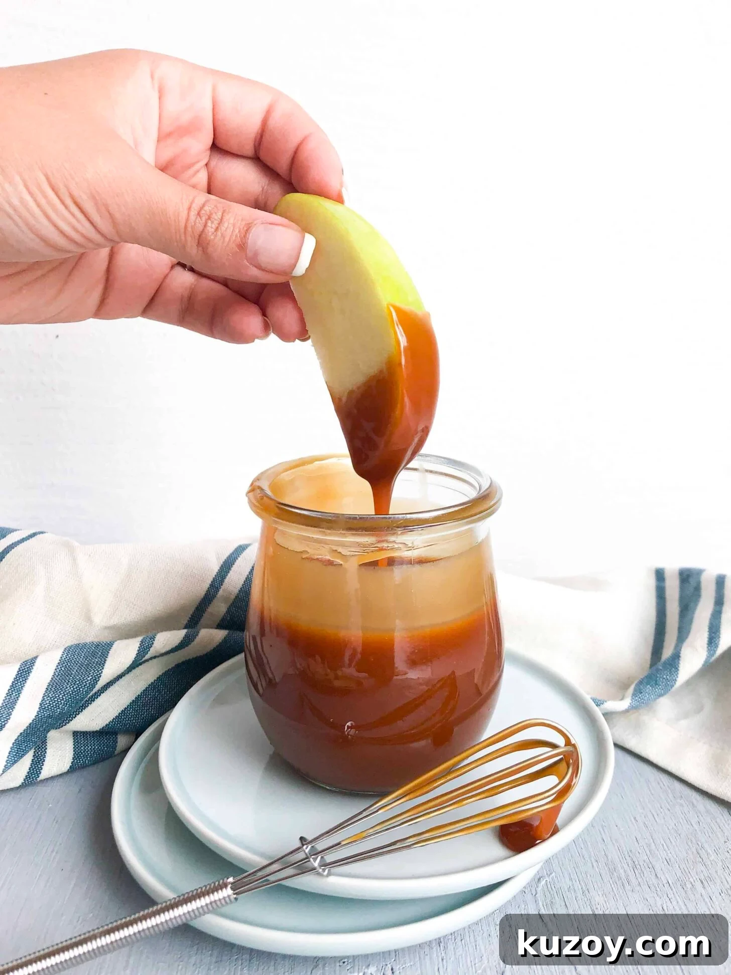 A green apple dipping into a jar of caramel