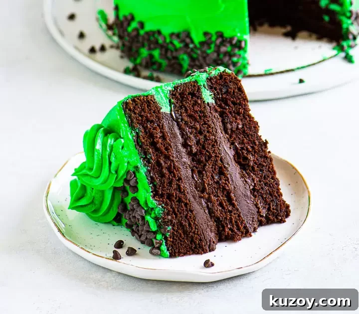 Decadent Chocolate Mint Cake Recipe with Fudgy Frosting 2 slice of cake on a plate with the rest of the cake in the background on a cake plate