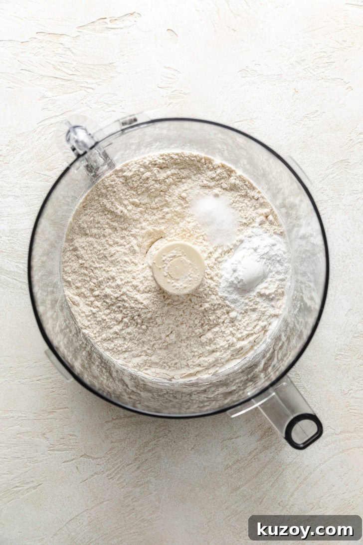 Flour, baking powder, and salt in a food processor bowl before mixing.