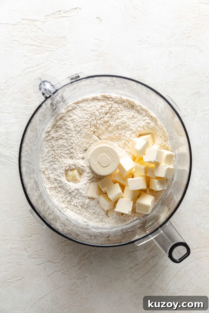 Cold cubed butter added to flour mixture in a food processor bowl.