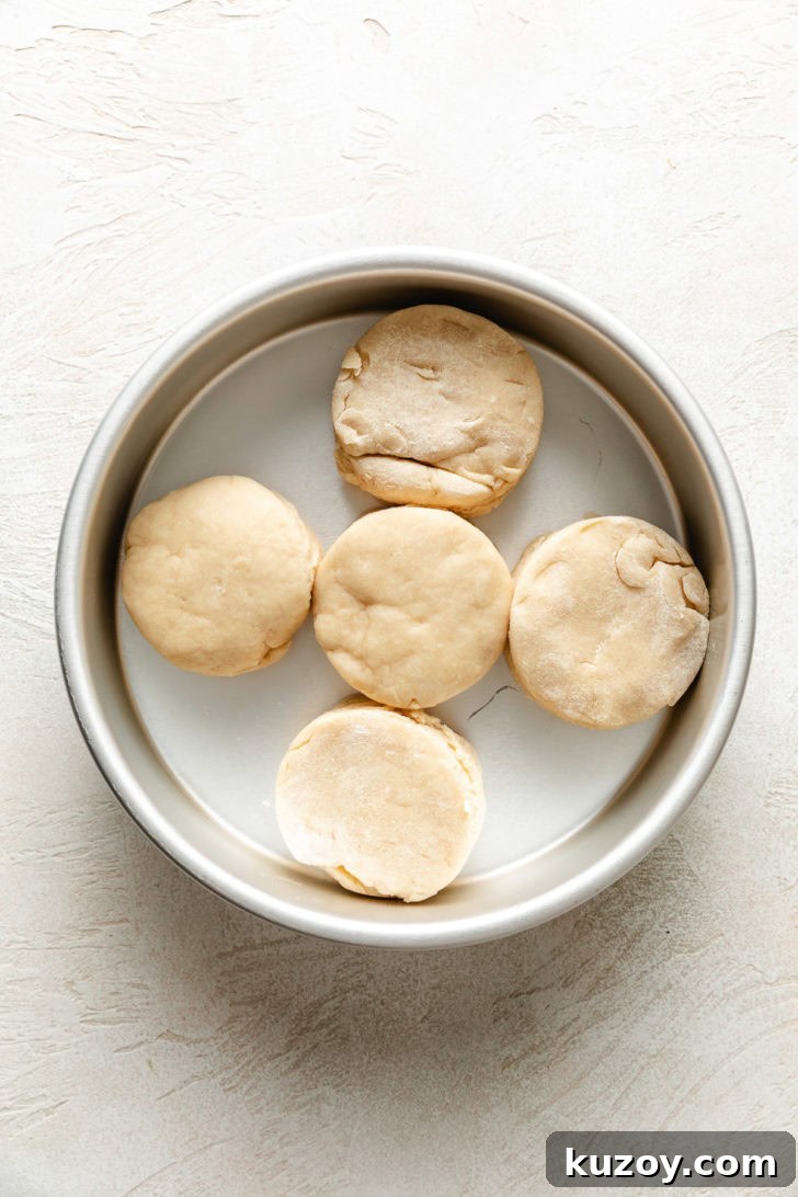 Five unbaked biscuits placed touching each other in a round cake pan.