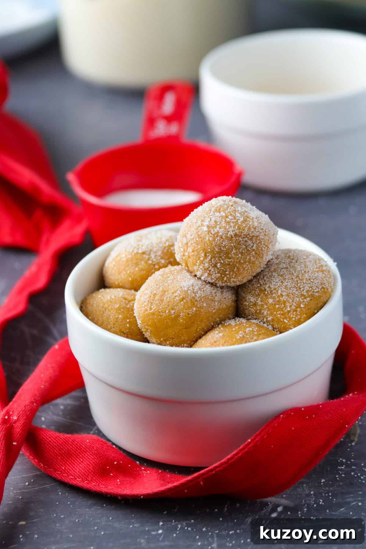 No-Cook Caramel Pastillas in a white bowl with red ribbon and red measuring cup in the background.