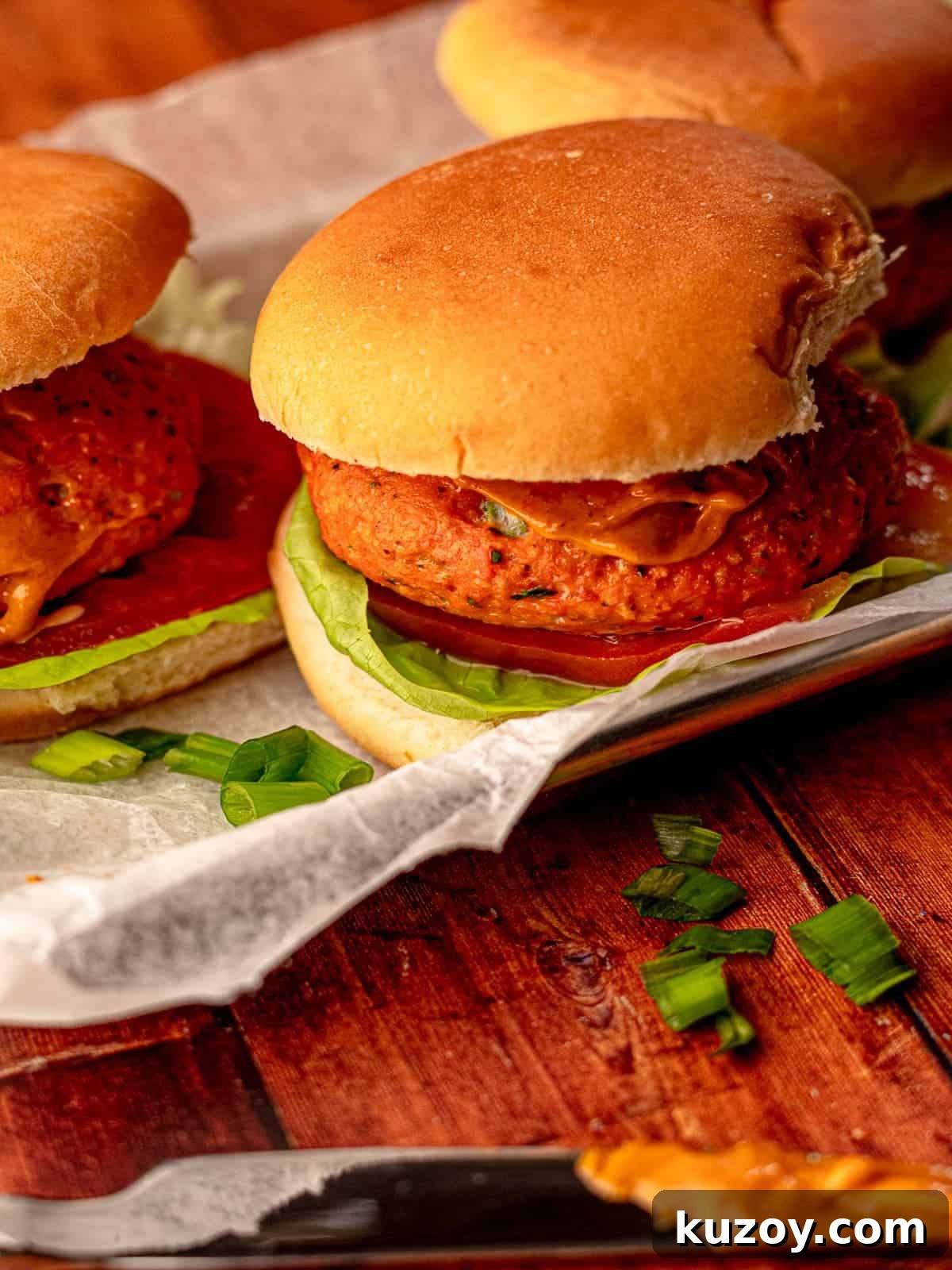 A salmon burger with lettuce tomato on a tray.