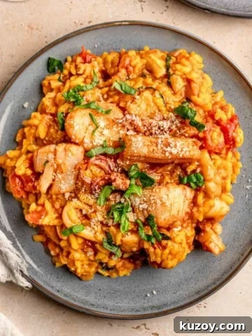 Seafood risotto topped with chopped basil on a plate.