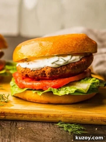 Salmon burgers with yogurt sauce on a cutting board.