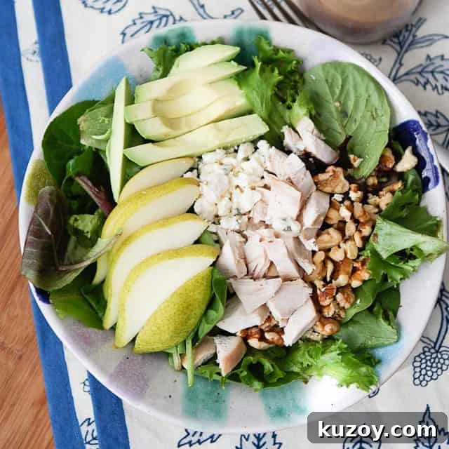Chicken, Pear & Avocado Salad with Honey-Lime Dressing 3 overhead photo of salad plate with greens, sliced pear, sliced avocado, chopped rotisserie chicken and walnuts