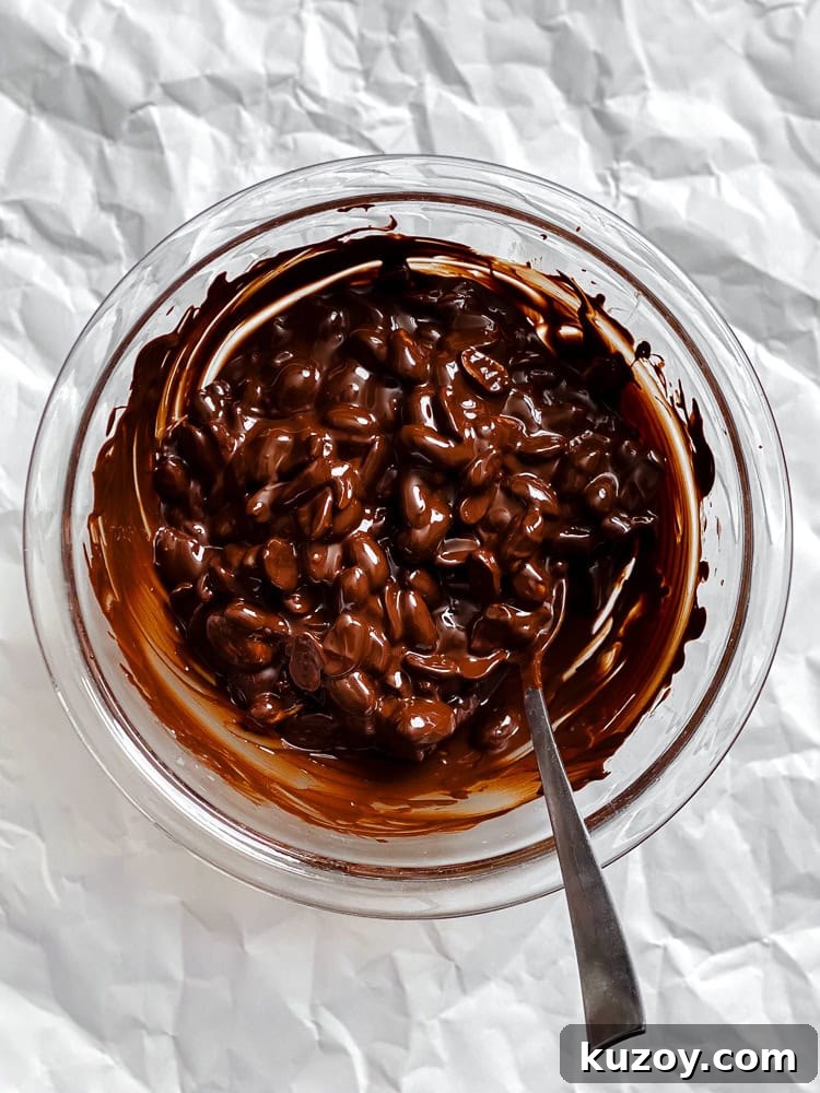 Process shot showing peanuts and vegan chocolate in a bowl.