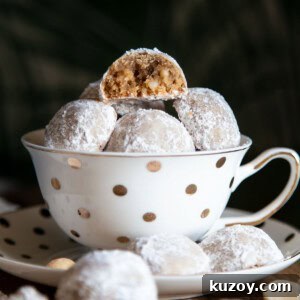 Snowball cookies in a tea cup with one half eaten cookie at top.
