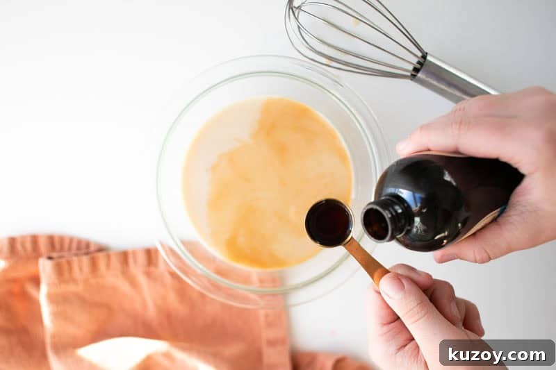 Snow Ice Cream Recipe Without Condensed Milk — Simple & Creamy 4 A cowl with milk and maple syrup in it. A teaspoon of vanilla extract is being added