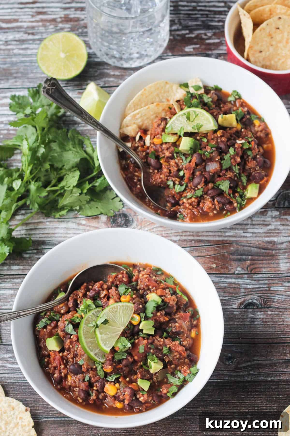 Hearty Black Bean and Quinoa Chili Recipe 8 Two white bowls of black bean quinoa chili with spoons in them.