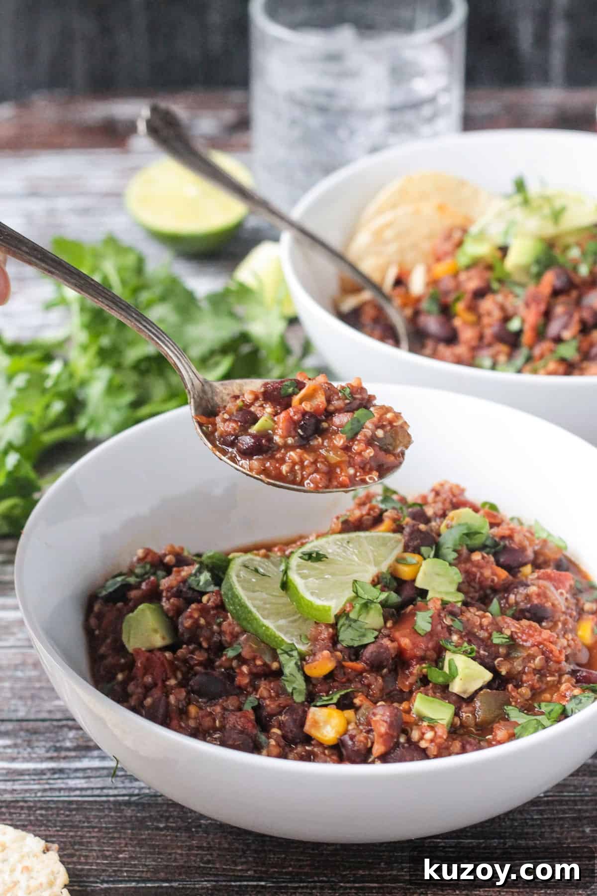 Black Bean Quinoa Chili - packed with protein and healthy veggies, this vegetarian chili is hearty and satisfying! Cocoa powder adds a delicious depth of flavor. Spoonful of chili with black beans and quinoa being lifted out of a white bowl.