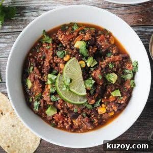 Hearty Black Bean and Quinoa Chili Recipe 13 Bowl of black bean quinoa chili topped with diced avocado and two lime slices.