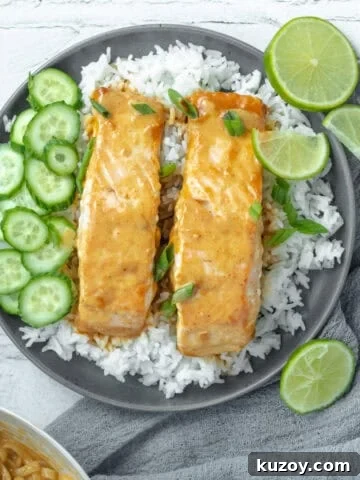 Thai red curry salmon on a bed of rice with limes and cucumbers.