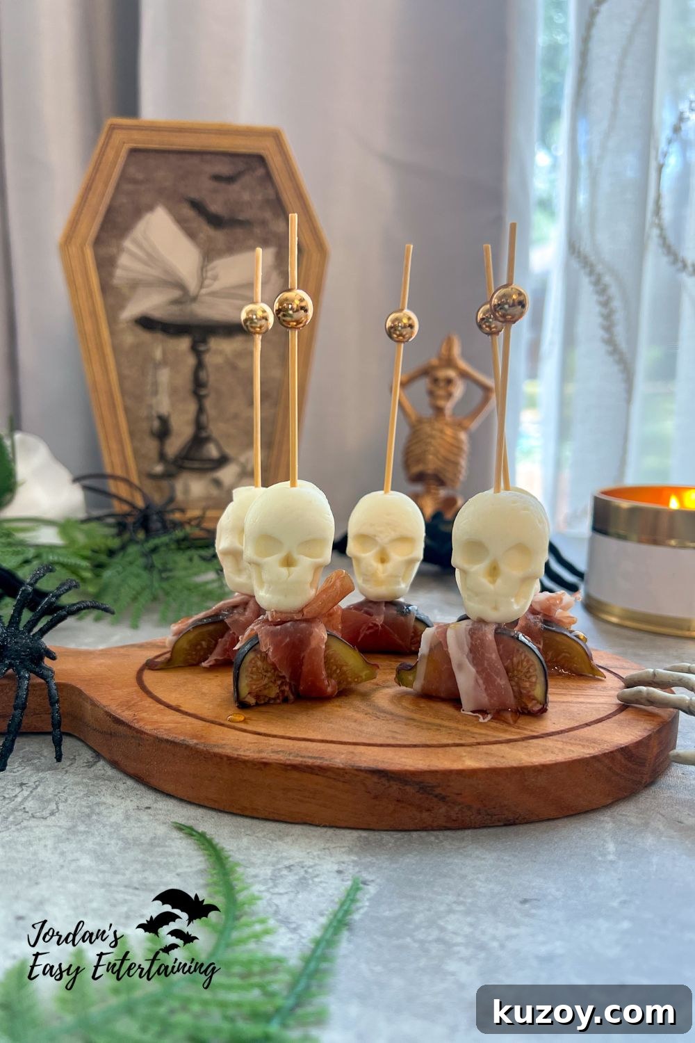 Prosciutto-Wrapped Figs with Honey and Skull Cheese Skewers 5 A savory Halloween appetizer of figs and prosciutto with mozzarella skull cheese bites and a drizzle of honey on a skewer served on a wooden platter