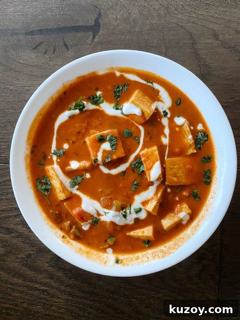 Paneer Makhani with Coconut Milk: Creamy Indian Curry Recipe 3 paneer makhani in a bowl on a hardwood floor backdrop