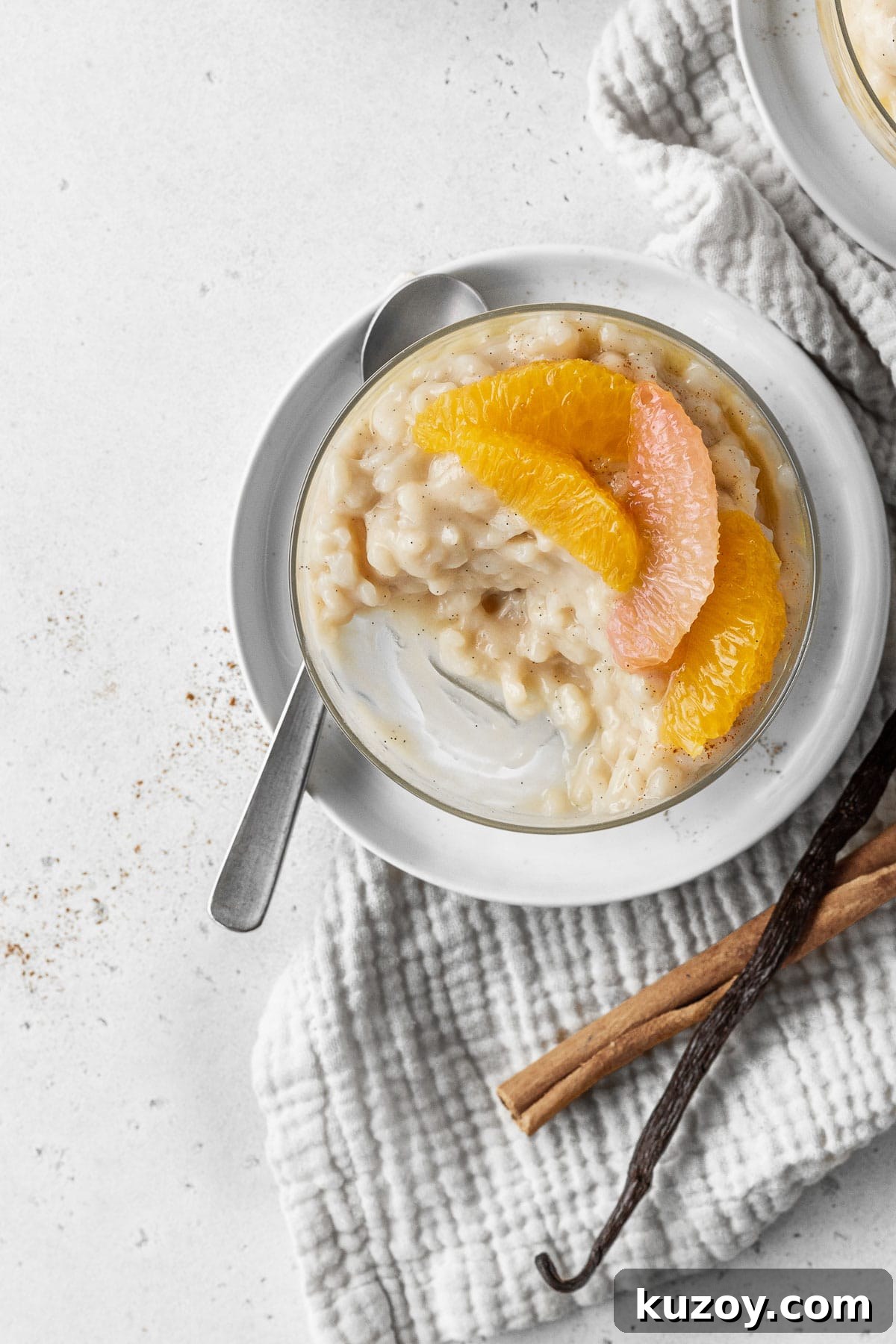 Creamy Dairy-Free Vegan Rice Pudding Recipe 12 A half eaten glass of vegan rice pudding with citrus segments on top.