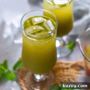 Two glasses filled with masala soda sit on a woven mat, with fresh mint leaves nearby.