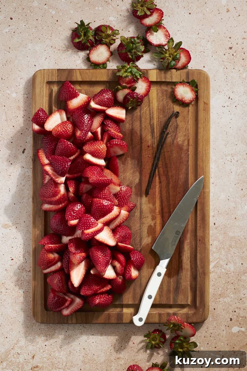 Strawberries sliced on a wooden cutting board.