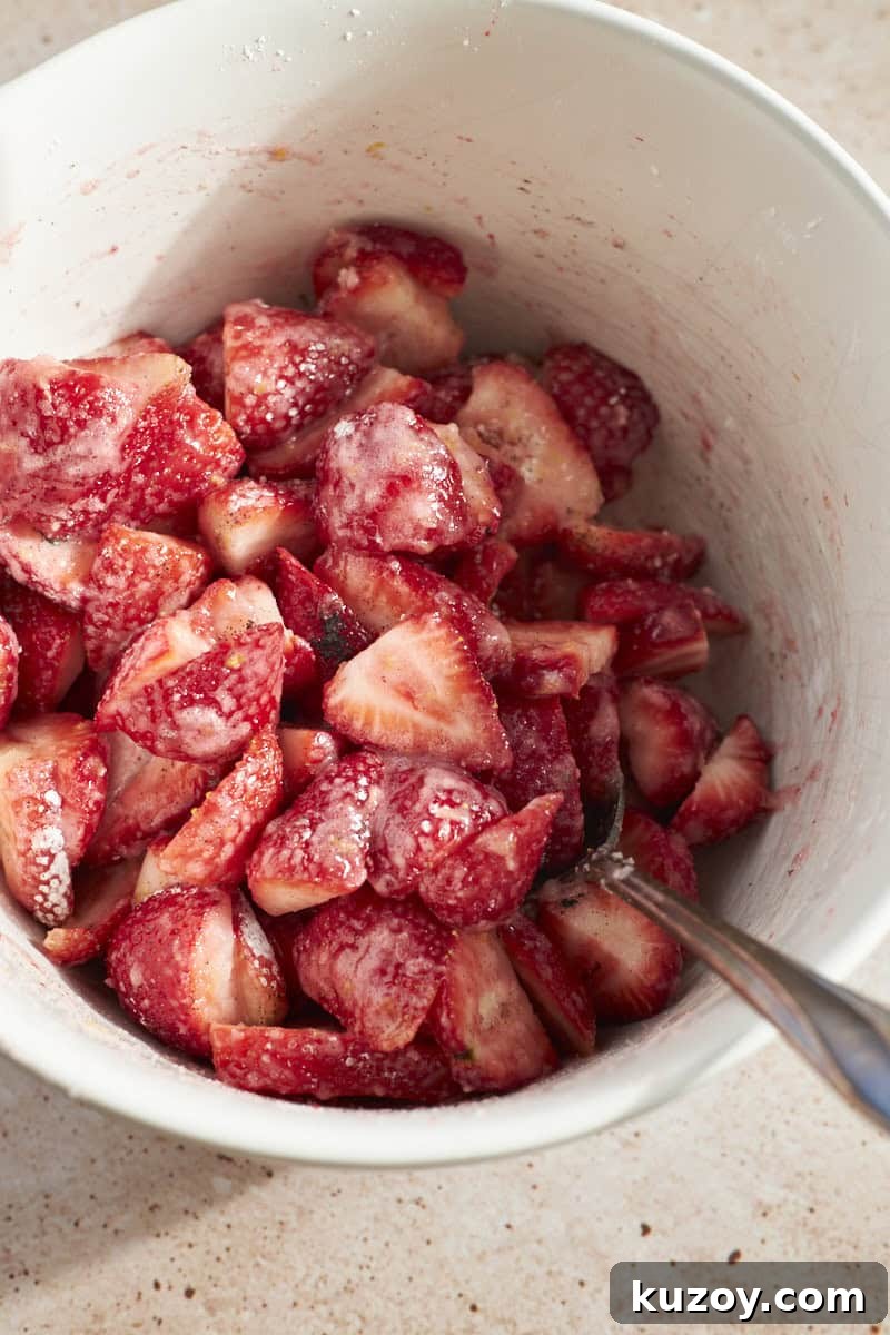 Strawberries mixed with other filling ingredients in a large bowl.