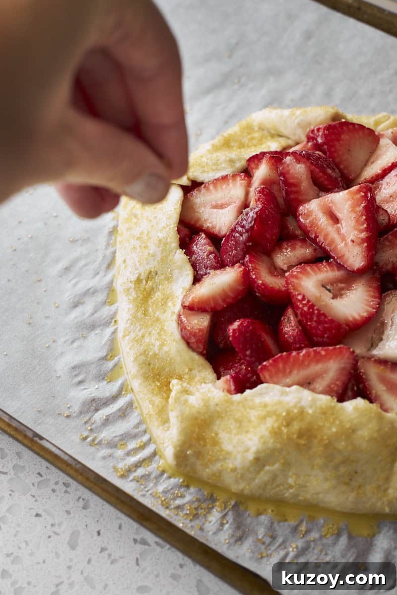 A hand sprinkling the galette with turbinado sugar.