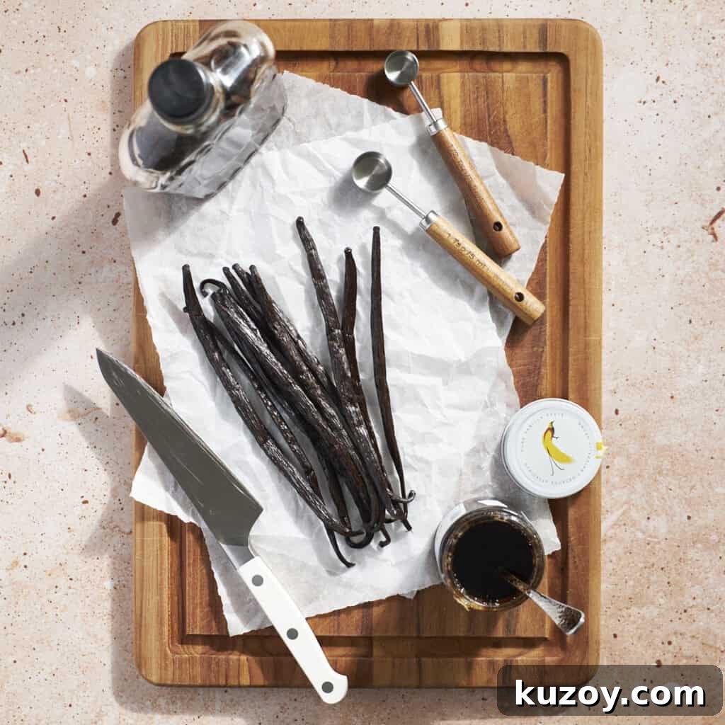 Vanilla extract, vanilla beans, and vanilla bean paste on a wooden cutting board.