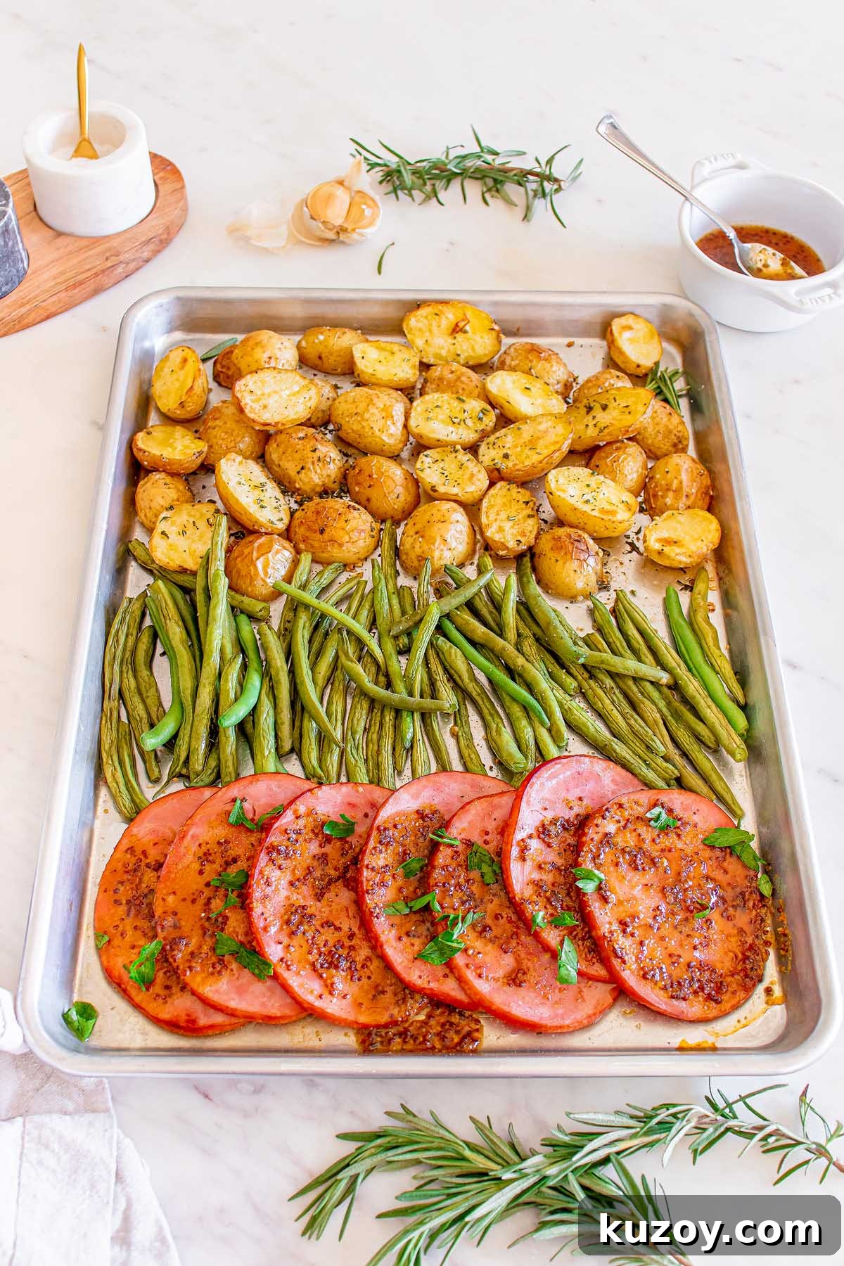 One-Pan Baked Ham Dinner with Roasted Vegetables 11 Roasted potatoes, green beans and sliced tomatoes topped with herbs on a sheet pan.