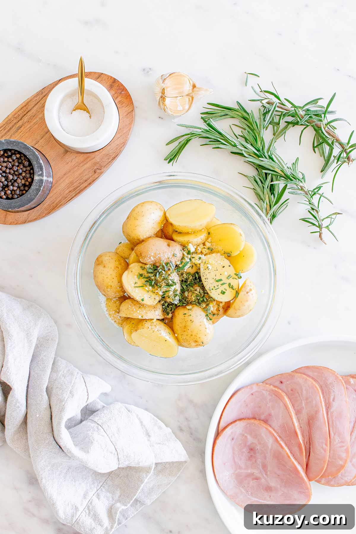 One-Pan Baked Ham Dinner with Roasted Vegetables 13 Bowl of seasoned halved potatoes with ham and herbs nearby.