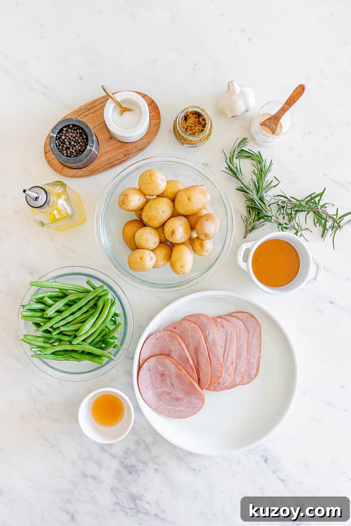 One-Pan Baked Ham Dinner with Roasted Vegetables 5 Ingredients arranged on a countertop: ham, potatoes, green beans, rosemary, garlic, olive oil and condiments.