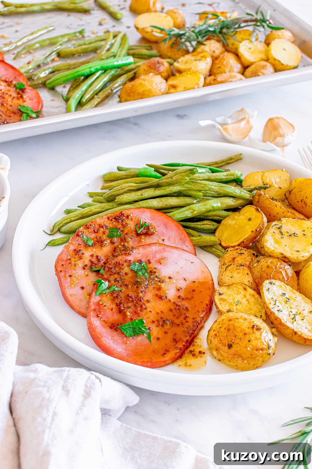 One-Pan Baked Ham Dinner with Roasted Vegetables 9 Plate with slices of ham, roasted green beans and golden potatoes.
