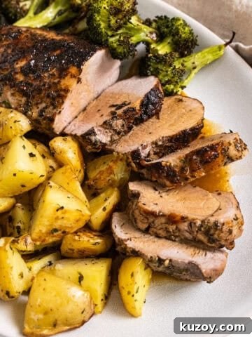 Sliced pork tenderloin served on a plate with roasted potatoes and broccoli.