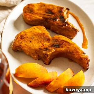 Peach Bourbon Glazed Pork Chops with Pan Sauce 15 Bourbon peach glazed pork chops on a plate garnished with peaches and extra sauce.