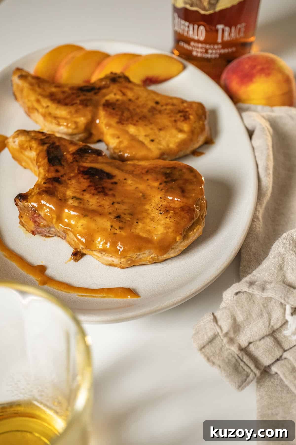 Peach Bourbon Glazed Pork Chops with Pan Sauce 10 Bourbon peach glazed pork chops on a plate garnished with peaches and extra sauce.
