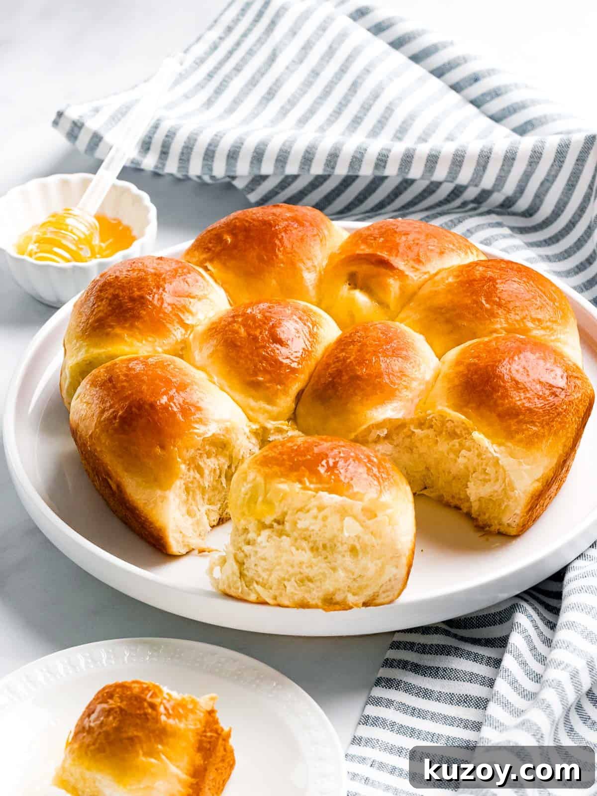 Homemade Brioche Rolls Recipe for Soft, Buttery Loaves 14 Soft buttery brioche rolls baked until golden brown next to a small bowl of honey.