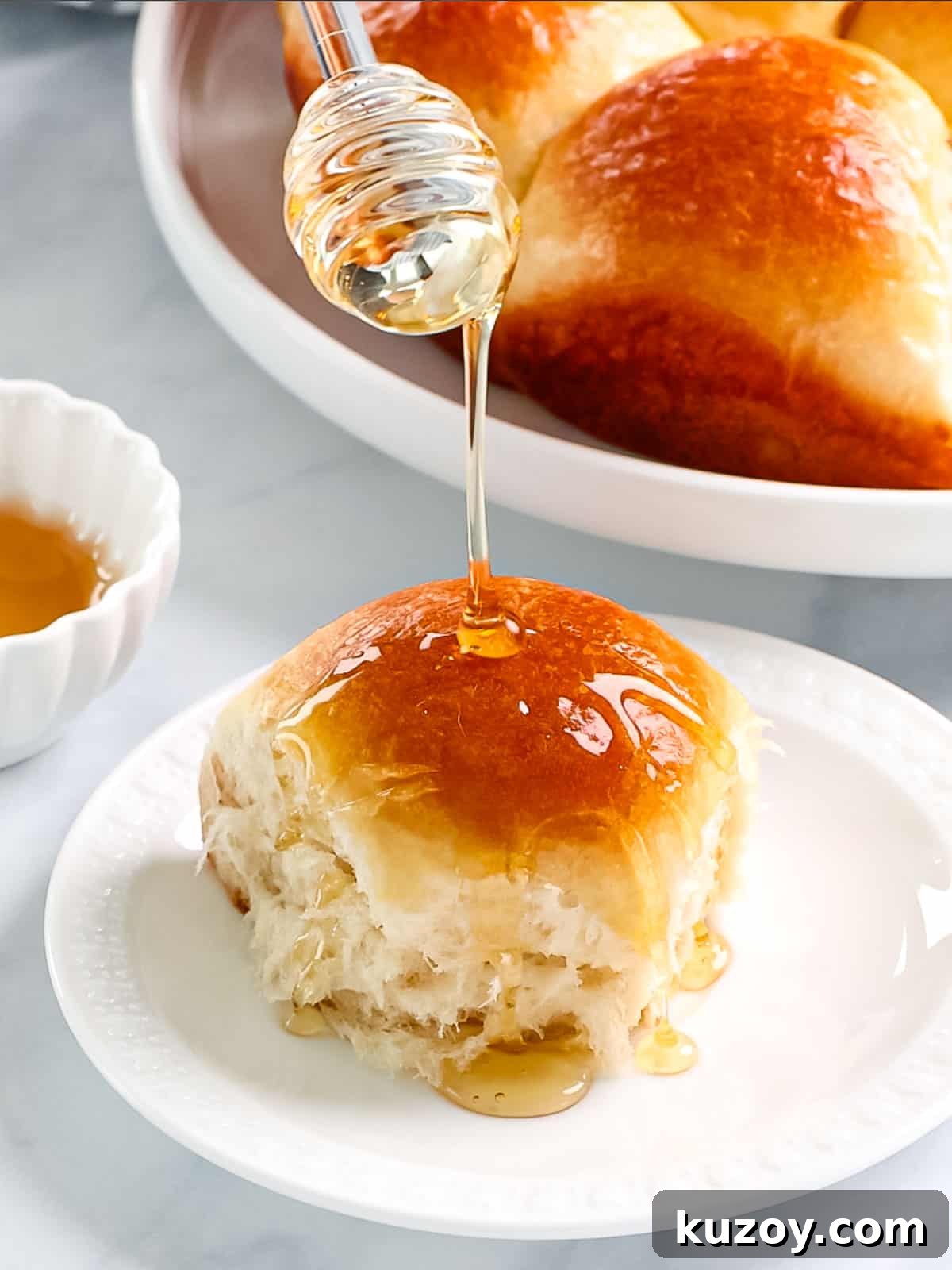 Homemade Brioche Rolls Recipe for Soft, Buttery Loaves 4 Buttery brioche rolls being drizzled with honey.
