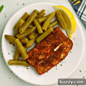 Overhead photo of air fried Mahi Mahi on a white plate with green beans and a lemon slice.