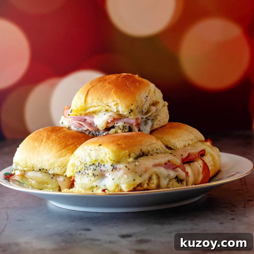 A pile of ham biscuits with Swiss cheese melting down the sides on a white plate with a background of twinkly holiday lights.