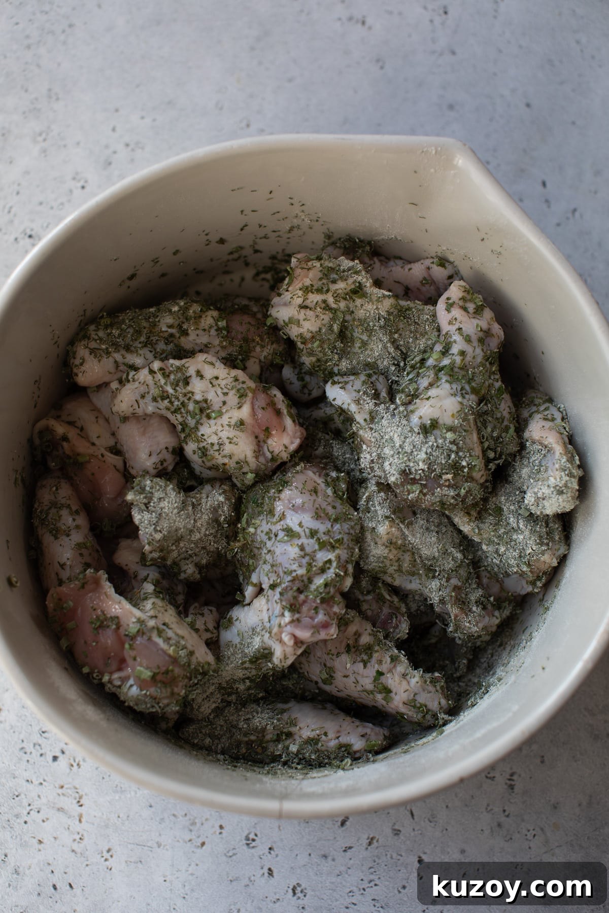 chicken wings in a large bowl with herbs on top