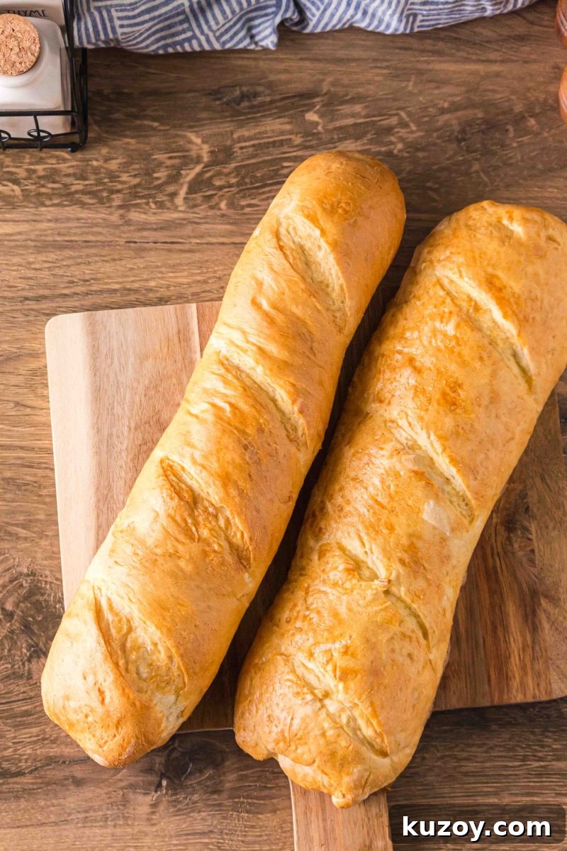 Two golden-brown homemade French Bread baguettes on a cutting board - Hostess At Heart