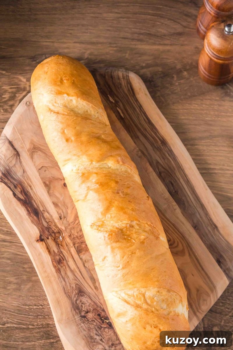 A baked golden-brown French baguette on a cutting board ready for slicing – Hostess At Heart